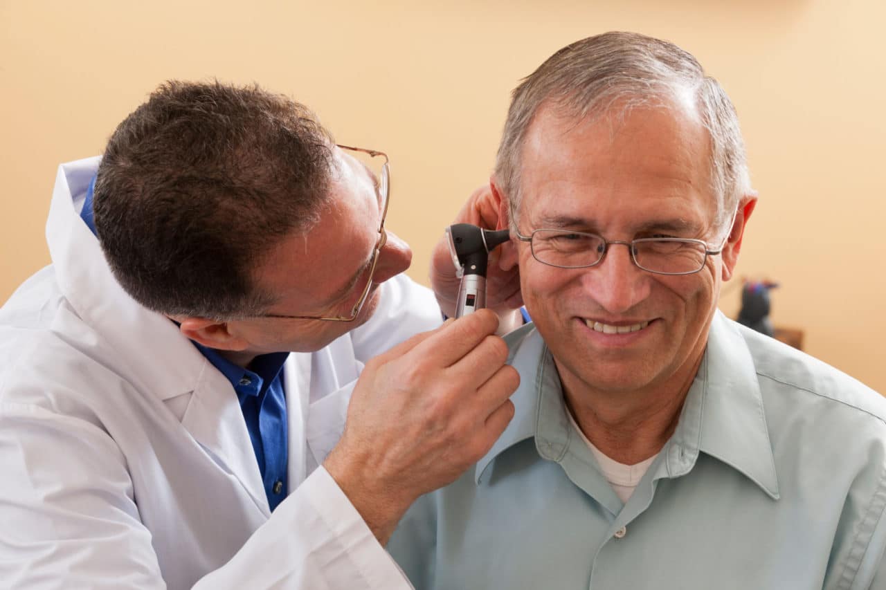 A provider inspecting a patient with an otoscope