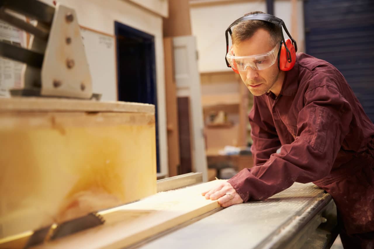 Photo of a person wearing protective headphones while doing woodwork with power tools