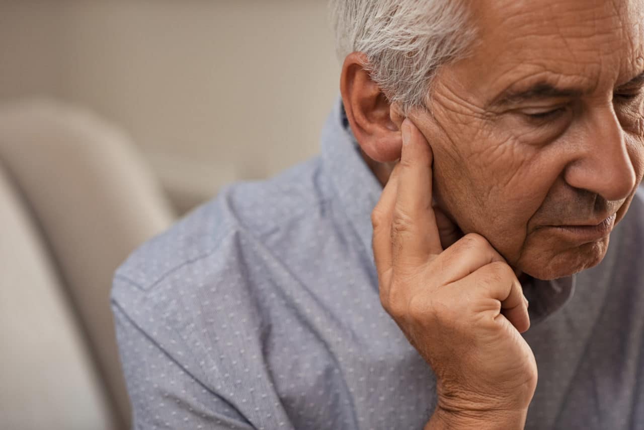 Photo of a man touching his ear with a worried expression