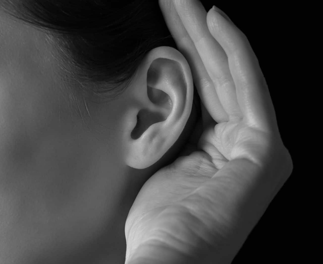 A person cupping a hand around their ear