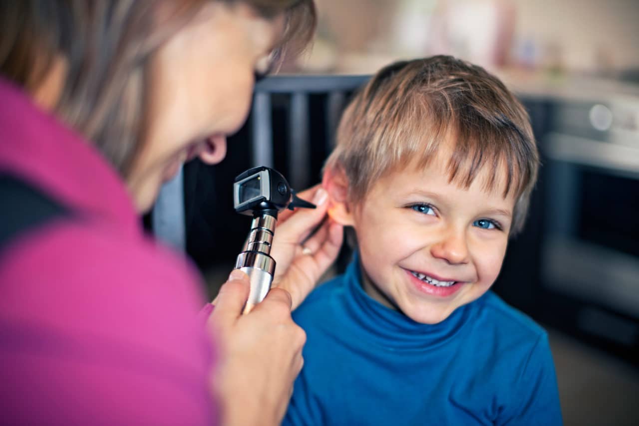 A provider examining a child with an otoscope