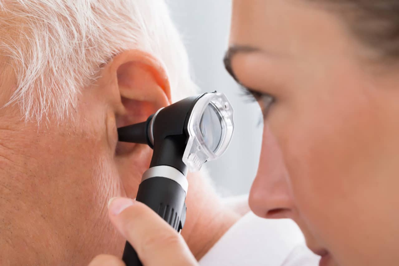 A provider examining a patient with an otoscope