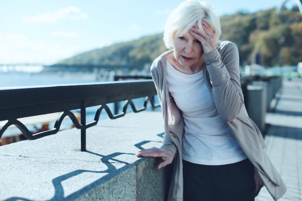 Photo of an older person holding their head cringing in pain