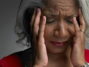 Photo of a person holding their head in both hands and wincing in pain