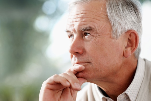 Photo of an elderly man holding his chin looking thoughtful