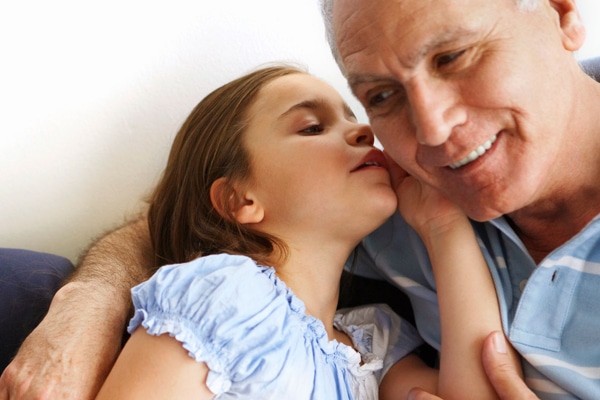 A child whispering into an older person's ear