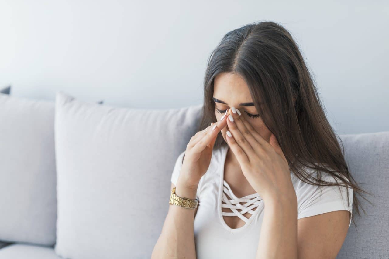 Woman experiencing sinus pressure at home.