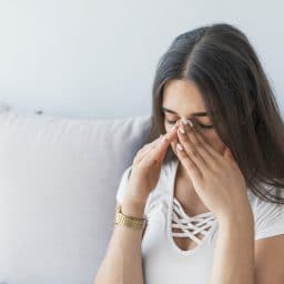 Woman experiencing sinus pressure at home.