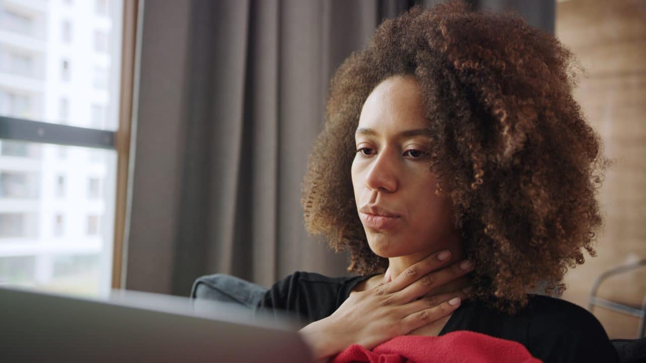 Woman feeling her throat.