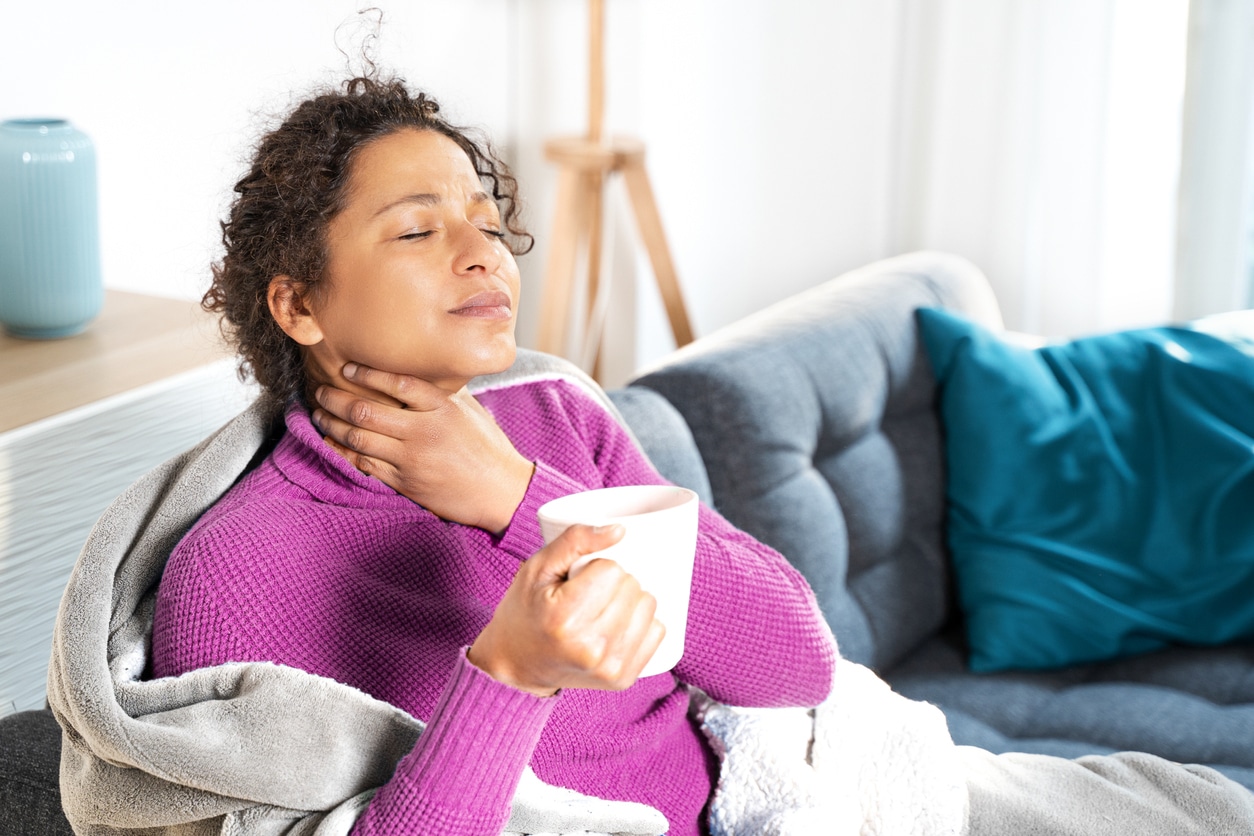 Woman with sore throat sips tea