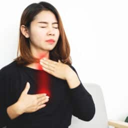 Woman with acid reflux holding her chest and throat.