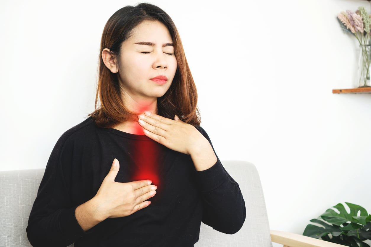 Woman with acid reflux holding her chest and throat.