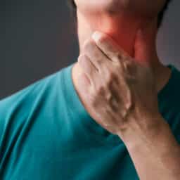 Man holding inflamed throat