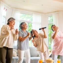 Elderly women singing karaoke at home.