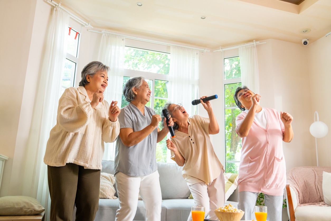 Elderly women singing karaoke at home.