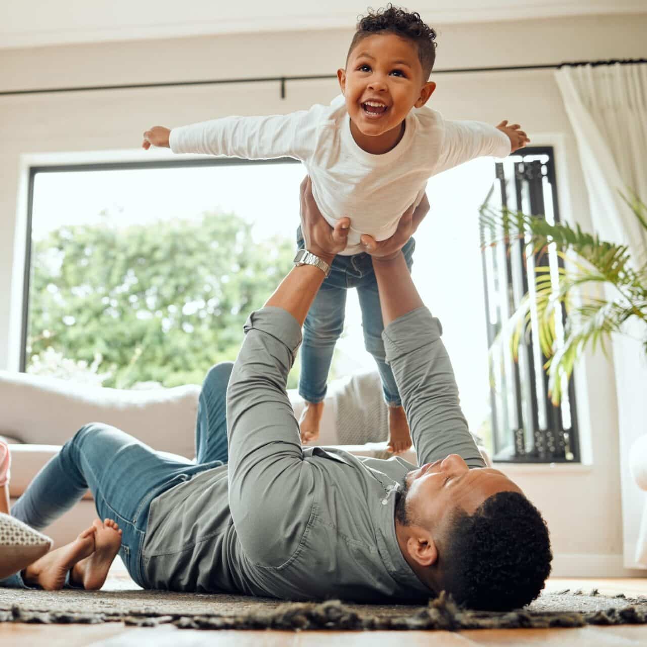 Father lifts his smiling child into the air.