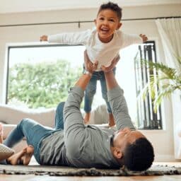 Father lifts his smiling child into the air.