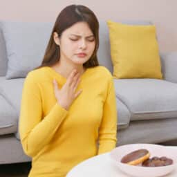 Woman experiences silent reflux after drinking a caffeinated beverage and eating sugary food.